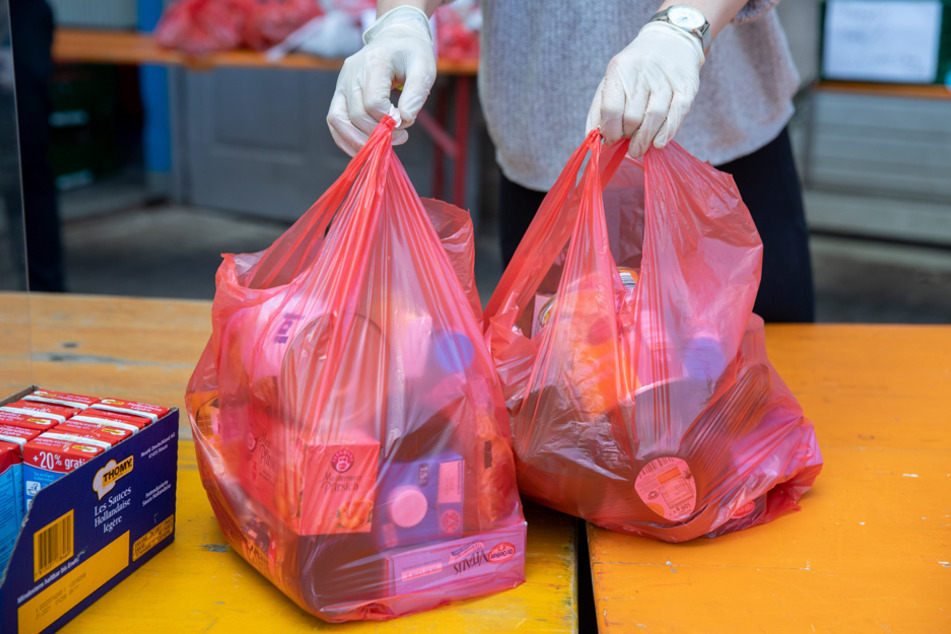 Lebensmittel in Plastiktüten werden gepackt und an Zäune gehängt.