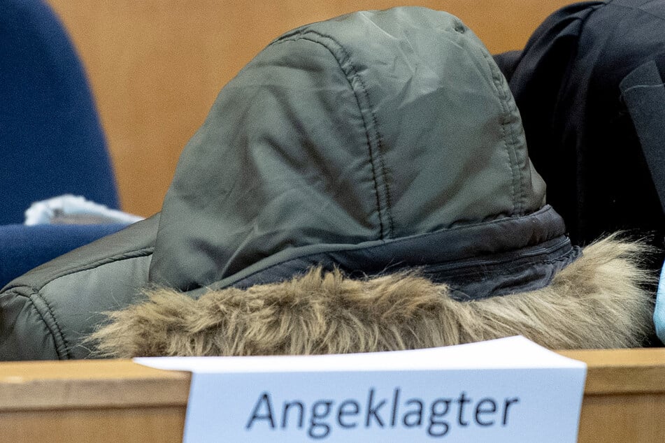 Der aus Syrien stammende angeklagte Arzt sitzt im Sicherheitssaal des Oberlandesgerichts in Frankfurt und verbirgt sein Gesicht unter einer Kapuze. (Archivfoto)