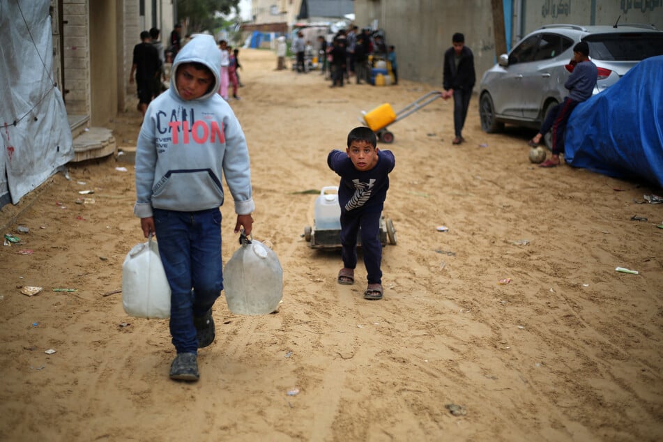 Displaced Palestinian children transport canisters filled with water at the Nuseirat refugee camp, in the central Gaza Strip, on April 1, 2026.