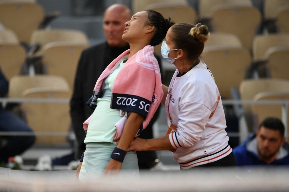 China's Zheng Qinwen (c) receives menstrual medical treatment during her singles match of the Roland-Garros Tournament.