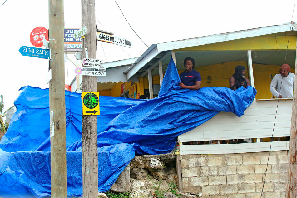 People in Bathsheba, Barbados, wrap up a tarpaulin after Tropical Storm Bret passed north of the island.