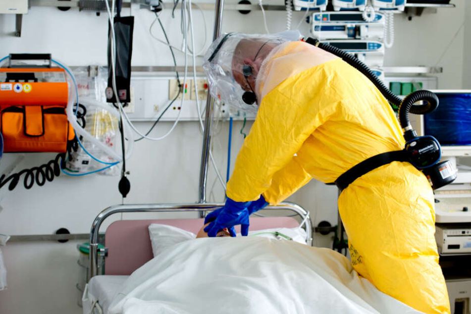 Ein Mann in Schutzausrüstung demonstriert bei einem Pressetermin die Versorgung eines Patienten auf der Sonderisolierstation im Klinikum Schwabing in München. (Symbolbild)
