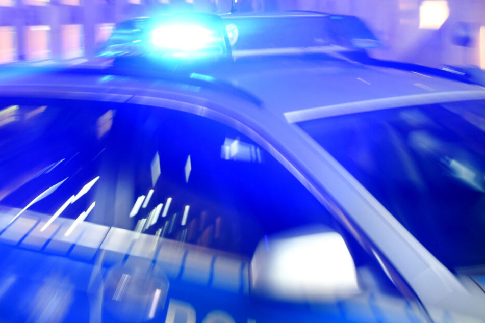 Ein Polizeifahrzeug steht mit eingeschaltetem Blaulicht auf einer Straße (Symbolbild).