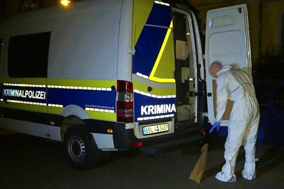 Kriminaltechniker kommen in Schutzanzügen zur Wohnung.
