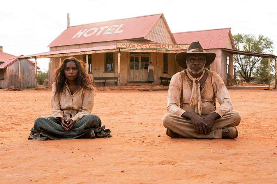 Sam Kelly (r., Hamilton Morris) und seine Frau Lizzie (l., Natassia Gorey Furber) warten in der Kleinstadt im australischen Outback vor der einzigen Kneipe.