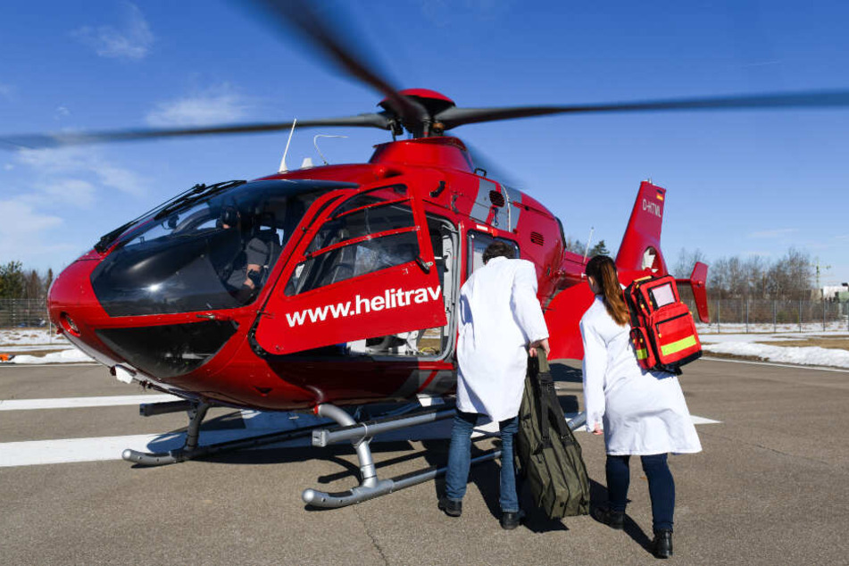 Ein Arzt und eine Mitarbeiterin der Klinik Harlaching in München steigen in einen Hubschrauber.