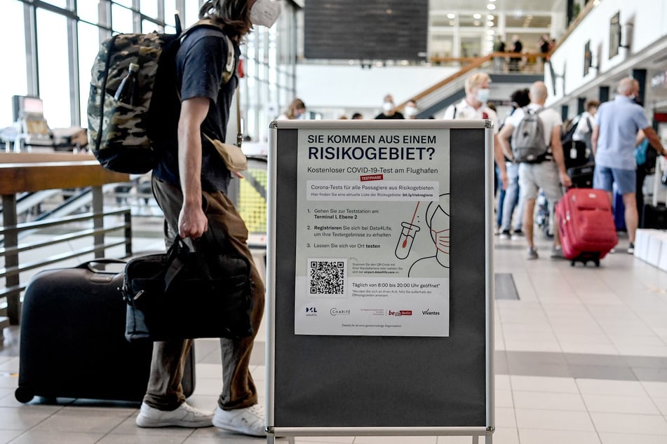 Schilder weisen auf die Corona-Teststelle am Flughafen Schönefeld hin.