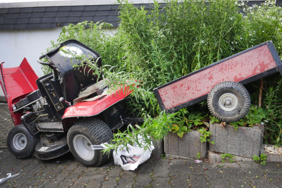 Ein Rasenmäher-Traktor steht nach einem Unfall an einer Hecke.