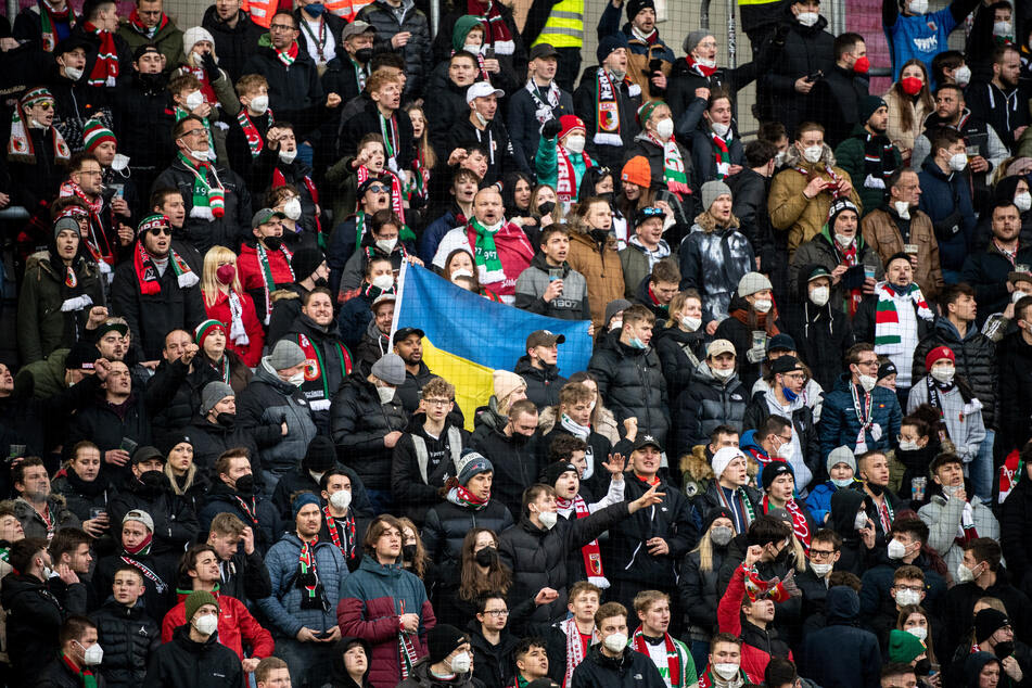 Fans in den deutschen Fußballstadien haben unter anderem Flaggen der Ukraine dabei - wie beispielsweise in Augsburg.