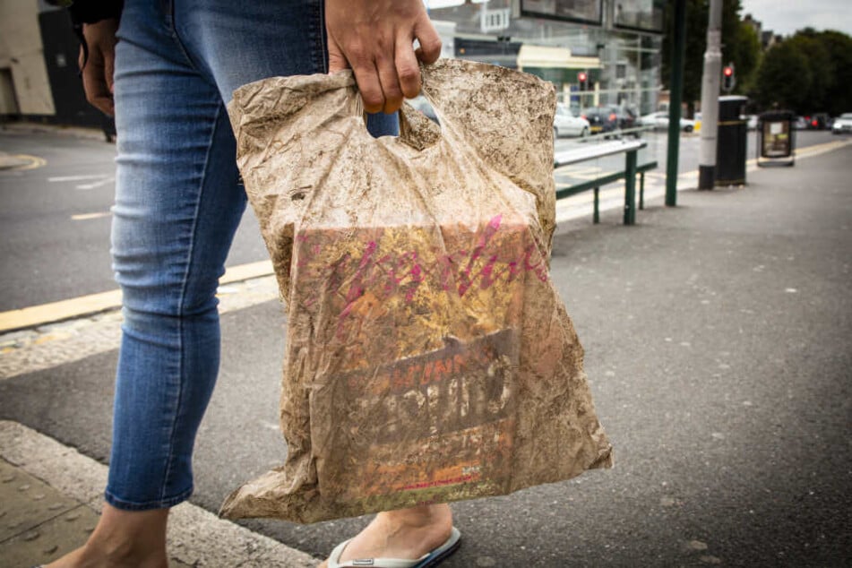 Eine Frau trägt eine Plastiktüte, die drei Jahre lang Umwelteinflüssen ausgesetzt war.