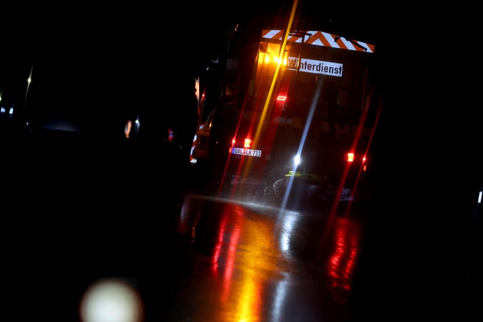 Ein Räum- und Streufahrzeug des Winterdienstes ist am frühen Morgen auf einer glatten Straße bei Marktoberdorf unterwegs.