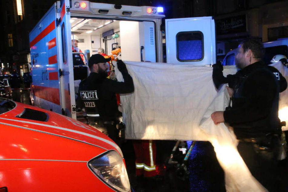 Mit Sichtschutz wird der schwer verletze Mann in den Rettungswagen gebracht.
