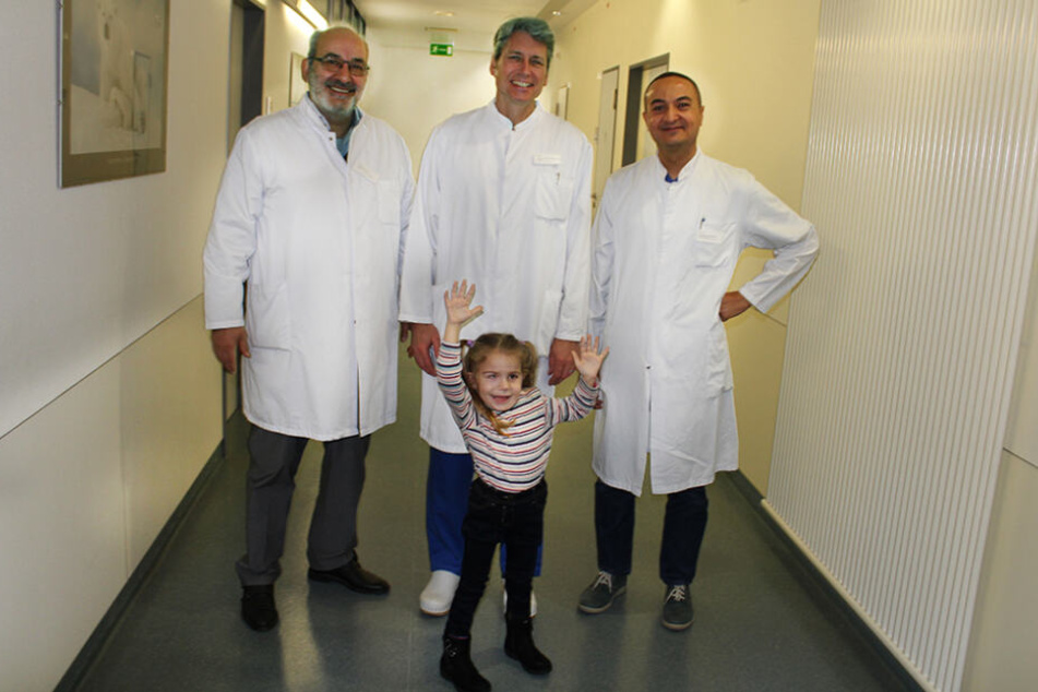 Die kleine Jara mit ihren Ärzten: (v.re.) Ph.D. Ahmed Shawky, Oberarzt für Wirbensäulenchirurgie, Dr. med. Ali Ezzati, Chefarzt der Wirbelsäulenchirurgie und Prof. Dr. med. Rüdiger Gerlach, Chefarzt der Neurochirurgie.