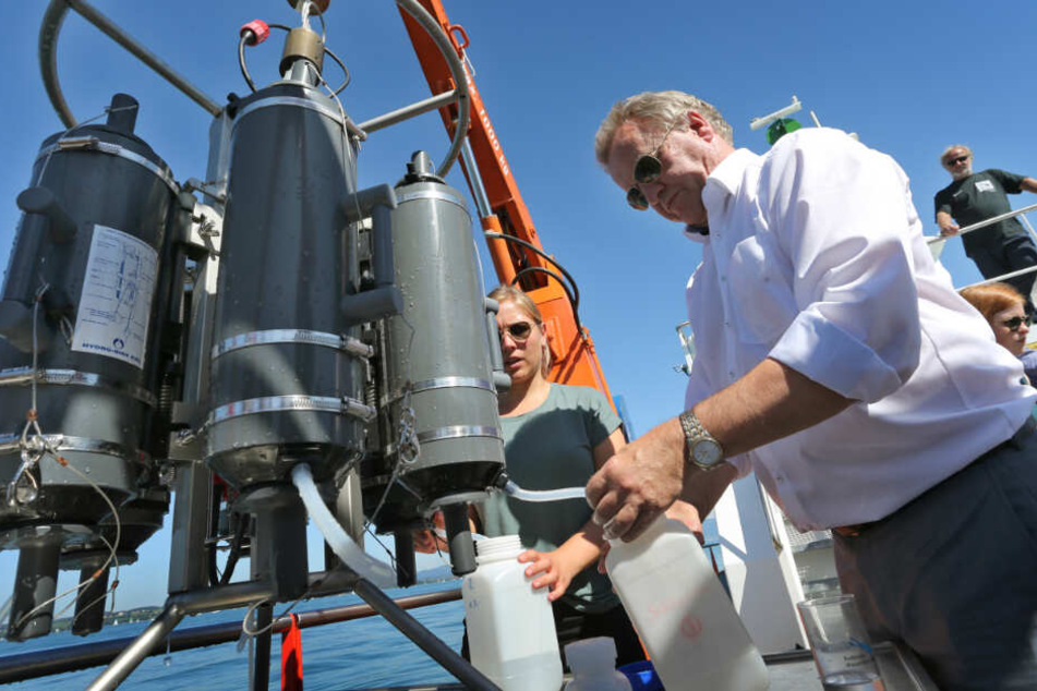 Umweltminister Franz Untersteller (rechts) entnimmt an Bord der "Kormoran" Wasser aus einem Wasserschöpfer.
