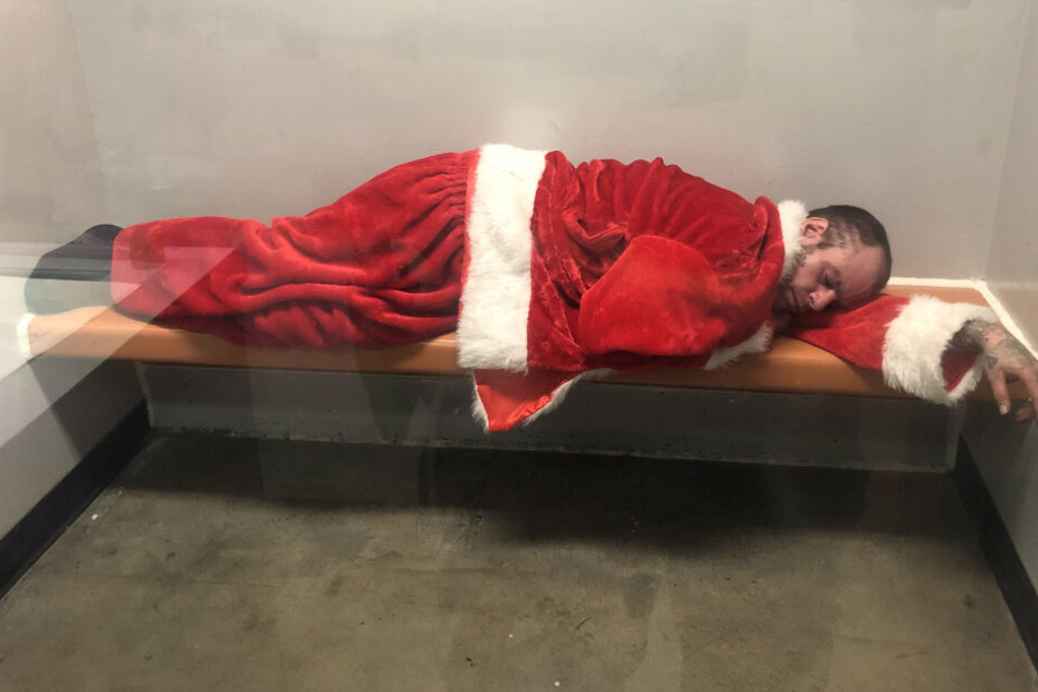 Santa Claus schläft in einer Gefängniszelle seinen Rausch aus.