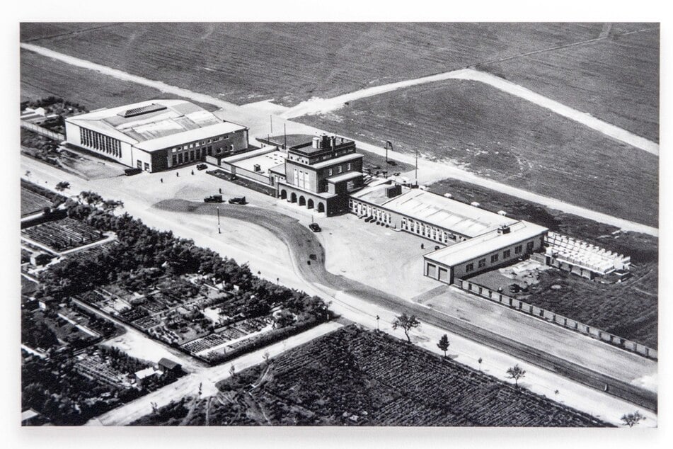 Das historische Foto zeigt die nach dem Zweiten Weltkrieg demontierte Flugzeughalle links neben dem Hauptgebäude und das Rollfeld.