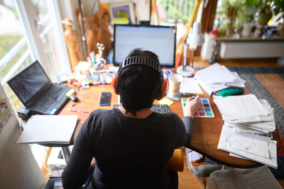 Eine Frau arbeitet mit Hörschutz im Homeoffice. Laut einer aktuellen Umfrage unter IT-Experten dürfte das Arbeiten von zu Hause aus auch unabhängig von Corona als Langzeitlösung bestehen bleiben. (Archivbild)