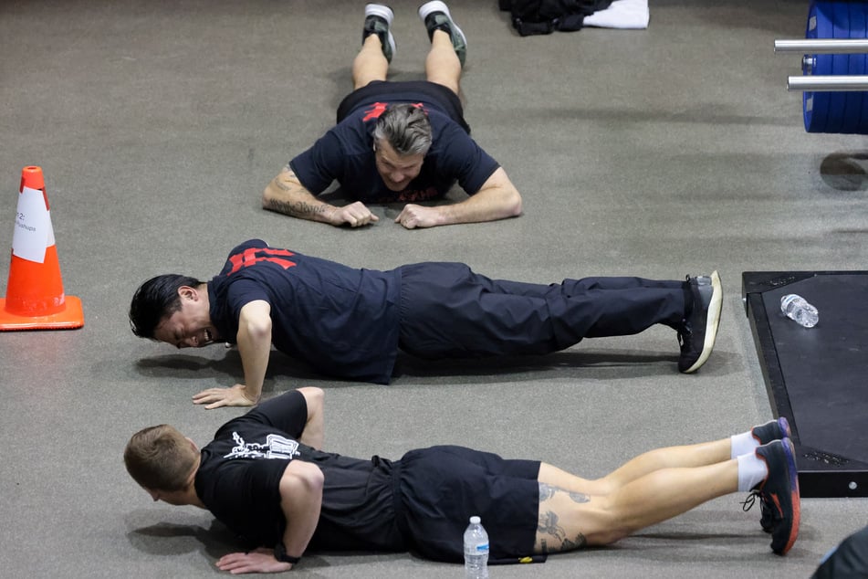 Japanese Defense Minister Shinjiro Koizumi (c.) reacts as he and US Secretary of Defense Pete Hegseth (top) train with US Army soldiers at Joint Base Myer-Henderson Hall in Arlington, Virginia, on January 15, 2026.