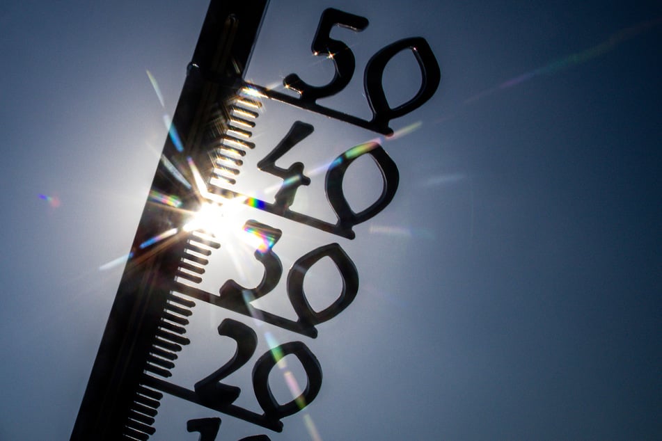 Vor einem wolkenlosen blauen Himmel zeigt ein Außenthermometer in einem Garten bereits am Vormittag über 30 Grad Lufttemperatur an.