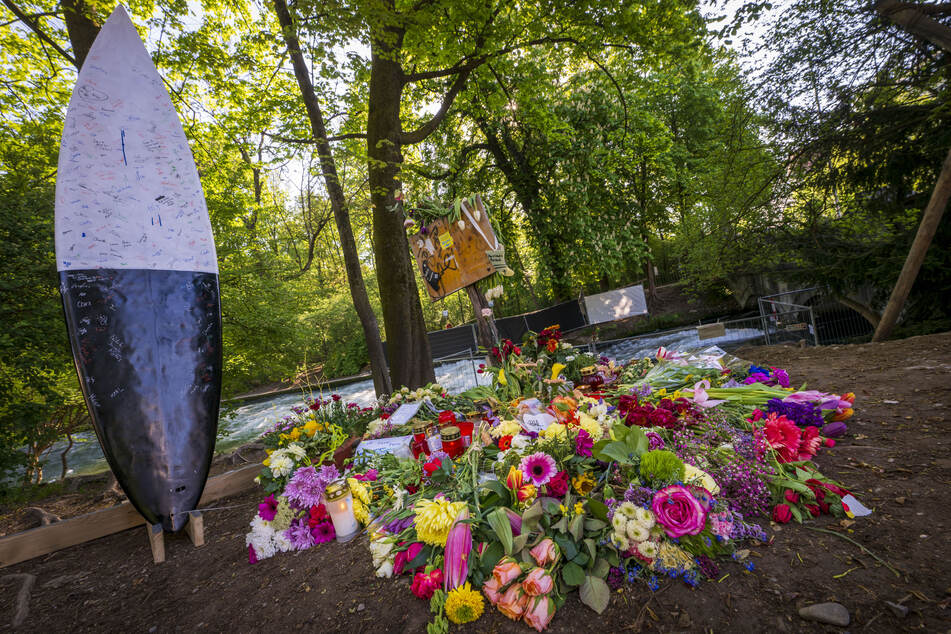 Blumen und Nachrichten wurden vor dem Absperrzaun am Ufer der Eisbachwelle im Englischen Garten hinterlassen.