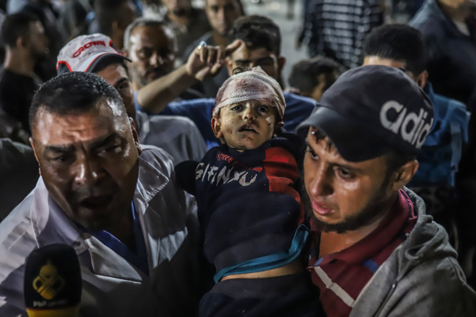 Palästinenser tragen ein verletztes Kind aus dem Ahli-Arab Krankenhaus in Richtung Schifa-Krankenhaus im Gazastreifen.