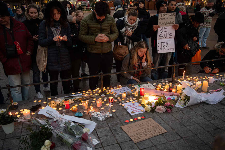 Nach dem Anschlag in Straßburg stehen Trauernde nahe dem Straßburger Weihnachtsmarkt hinter zahlreichen brennenden Kerzen.