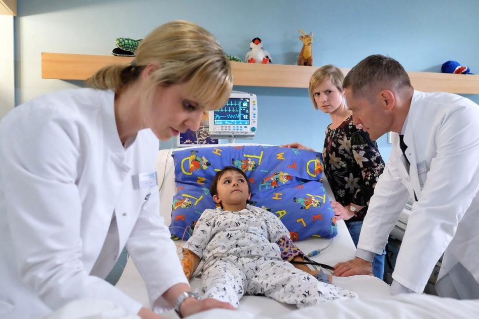Der kleine Fritz ist beim Spielen von einem Klettergerüst gefallen. Er hat sich dabei an der Wirbelsäule verletzt und kann seine Beine nicht mehr spüren. Seine Mutter Friederike (2.v.r.) ist in großer Sorge.