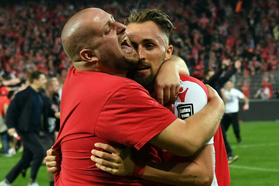 Hübner wird nach dem Aufstieg von einem Fan auf dem Platz umarmt.