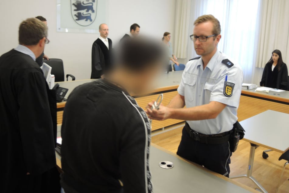 Der Gerichtssaal in Ulm: Dem Angeklagten (vorne) werden vor Beginn der Verhandlung die Handschellen abgenommen.