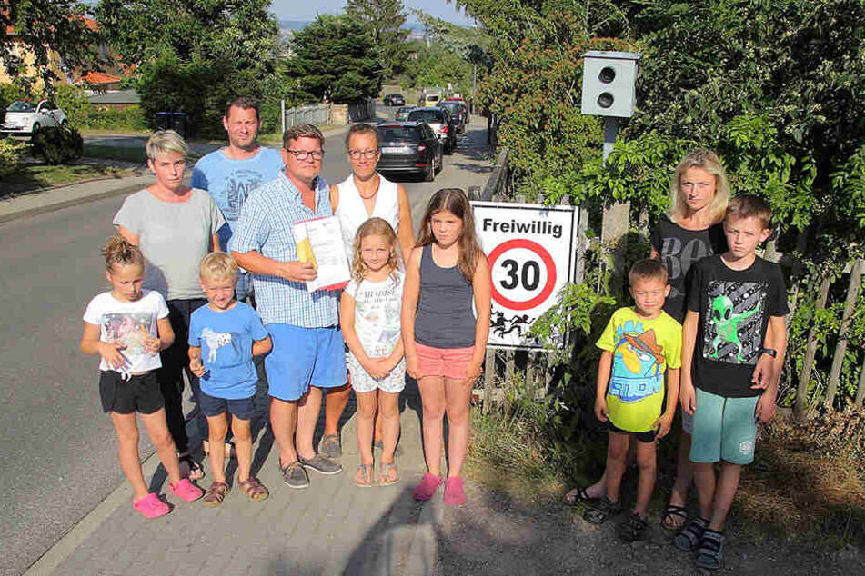 Familienvater Klaus D. (42, mit Bußgeldschreiben) und Mobschatzer Anwohner an der Blitzer-Attrappe und dem selbst gebastelten "Freiwillig 30"-Warnschild.