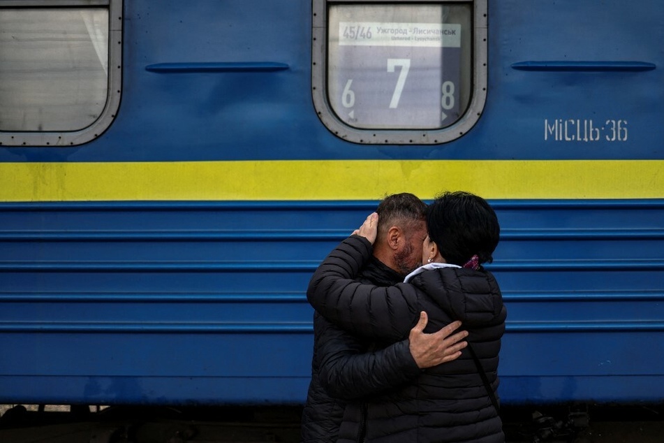 Ein Mann verabschiedet seine Frau, bevor sie den Zug in Slowjansk betritt. Das ukrainische Militär beobachtet derzeit eine Ansammlung russischer Truppen, die die Stadt anscheinend angreifen sollen.