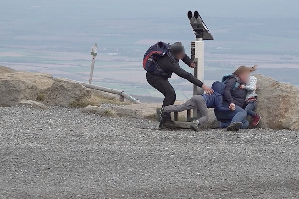 Eine Familie auf dem Brocken wird von den Sturmböen umgeweht.