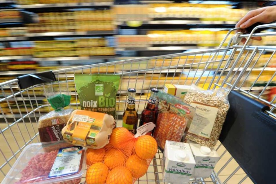 Ein Einkaufswagen mit verschiedenen Bio-Produkten wird durch einen Biomarkt geschoben