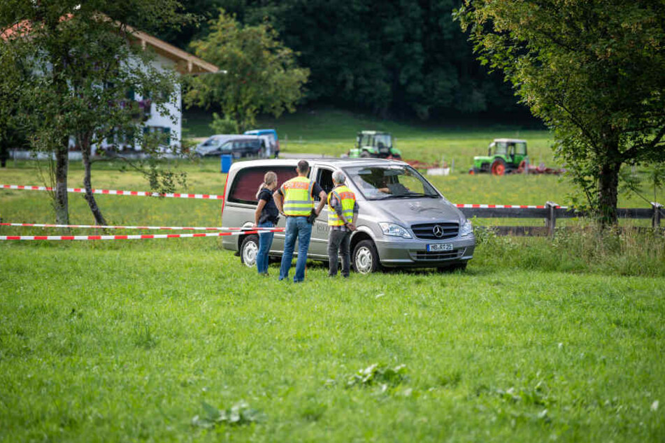 Das Fahrzeug eines Bestatters verlässt im Ortsteil Scharling einen abgesperrten Bereich an einem Bachlauf.