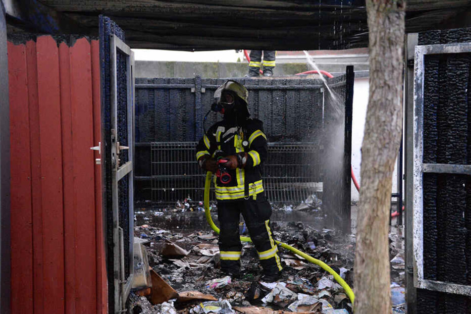 Ein Feuerwehrmann steht in dem völlig verkohlten Carport.