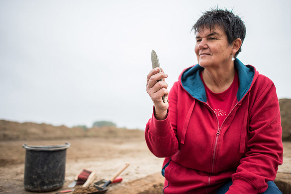 Maria Hahne, Grabungstechnikerin beim Landschaftsverband-Westfalen-Lippe (LWL), begutachtet die Beil-Spitze aus Stein.