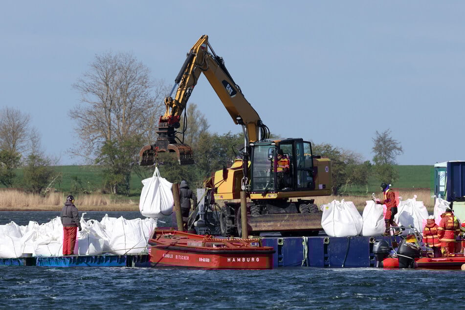 Eine schwimmende Plattform mit Dutzenden mit Sand gefüllten Big Bags wird zur Arbeitsplattform neben dem gestrandeten Buckelwal vor der Insel Poel geschleppt und dort entladen.