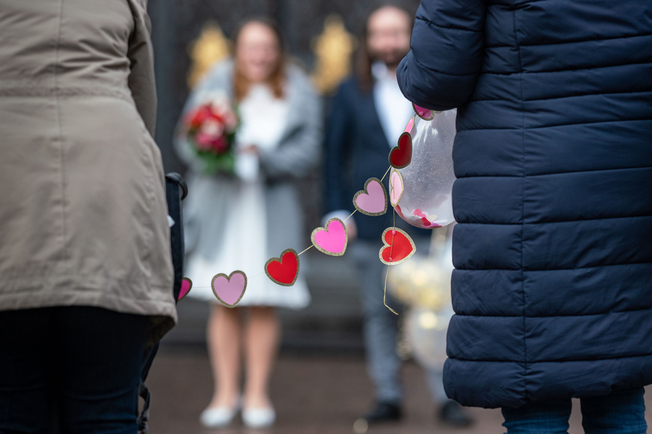 Ein Hochzeitspaar steht in großem Abstand zu seinen Gästen: In NRW ist die Zahl der Eheschließungen im Corona-Jahr 2020 auf einen historischen Tiefstand gesunken.