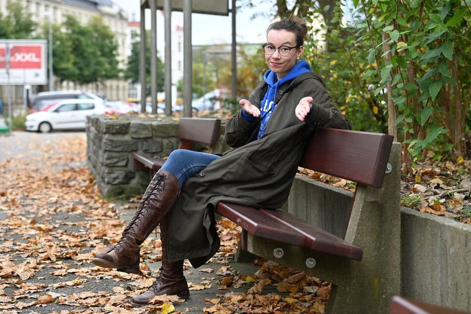 Volontärin Lena Plischke sitzt überrascht auf den neuen Sitzbänken am Richard-Hartmann-Platz.