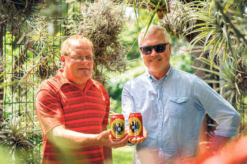 Lieferauftrag erledigt. Jens Teichert (56, l.) nimmt von MOPO-Reporter Torsten Hilscher (51) das Bier aus Costa Rica entgegen. Die Marke "Imperial" ist seine zweite große Leidenschaft neben den Bromelien, die ringsum hängen.