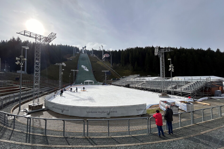 Panoramablick in die Vogtland Arena, die zum Eishockey-Stadion wird. Schaulustige Einheimische verfolgen die Aufbauarbeiten.