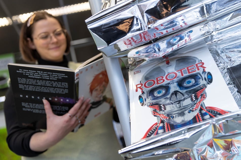 Die Auszubildende Luisa Kahnt (24) bietet Besuchern in der Chemnitzer Stadtbibliothek zahlreiche Medien zum Thema "Robotik" an.