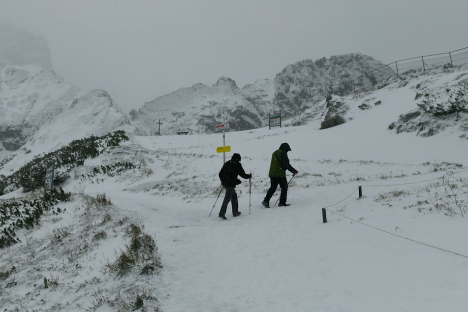 Wanderer sind nach einem Temperatursturz auf dem schneebedeckten Osterfelderkopf im Wettersteingebirge bei Garmisch-Partenkirchen unterwegs.