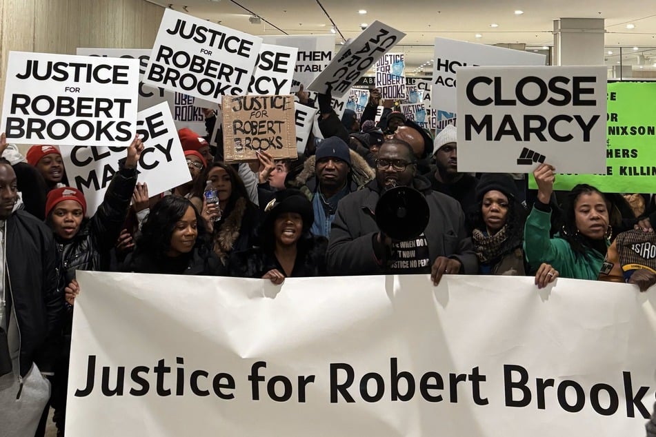 Activists rally outside New York Governor Kathy Hochul's State of the State address demanding justice for Robert Brooks.