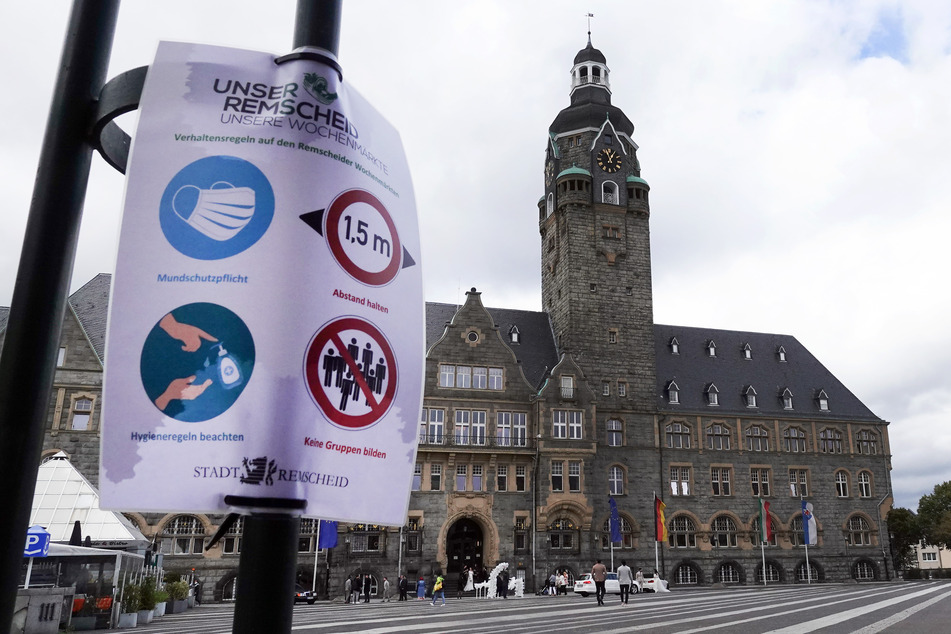 Auf einem Schild vor dem Rathaus sind Piktogtamme mit Verhaltensregeln zum Schutz vor einer Corona-Ansteckung zu sehen. In Remscheid sind die Corona-Fallzahlen stark gestiegen.