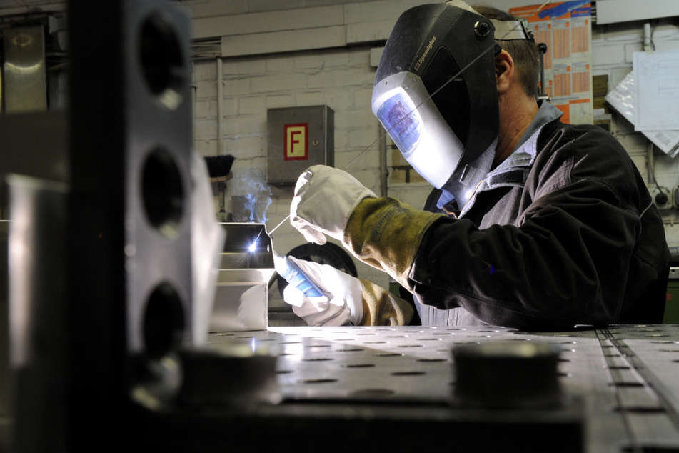 Ein Mitarbeiter eines metallverarbeitenden Betriebes schweißt eine Naht an einem Werkstück.