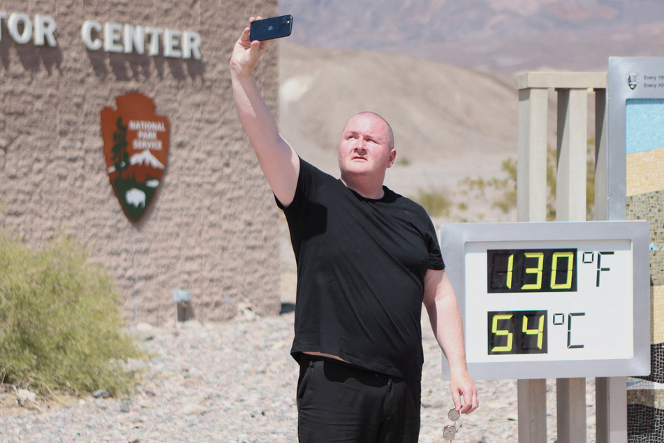Tourist Scott Hughes takes a selfie next to an unofficial heat reading at the visitor center in Death Valley National Park last weekend during a heat wave.