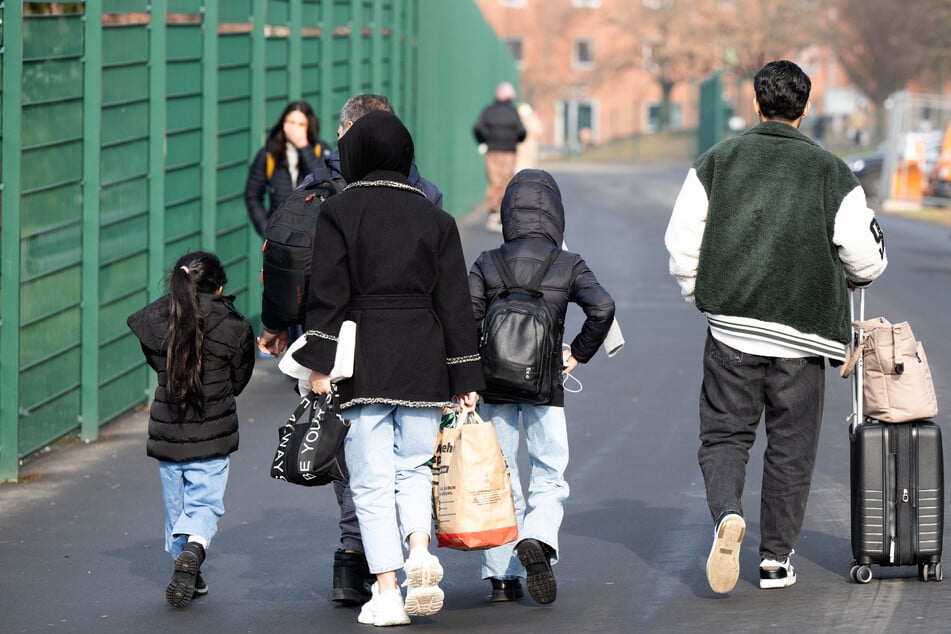 Flüchtlinge gehen in der hessischen Erstaufnahmeeinrichtung in Gießen zu einer Unterkunft.