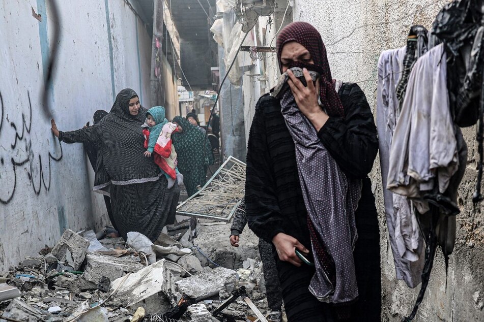 Palestinian people find their way through a rubble-covered alley, following overnight Israeli bombardment in Rafah in the southern Gaza Strip, on February 25, 2024.