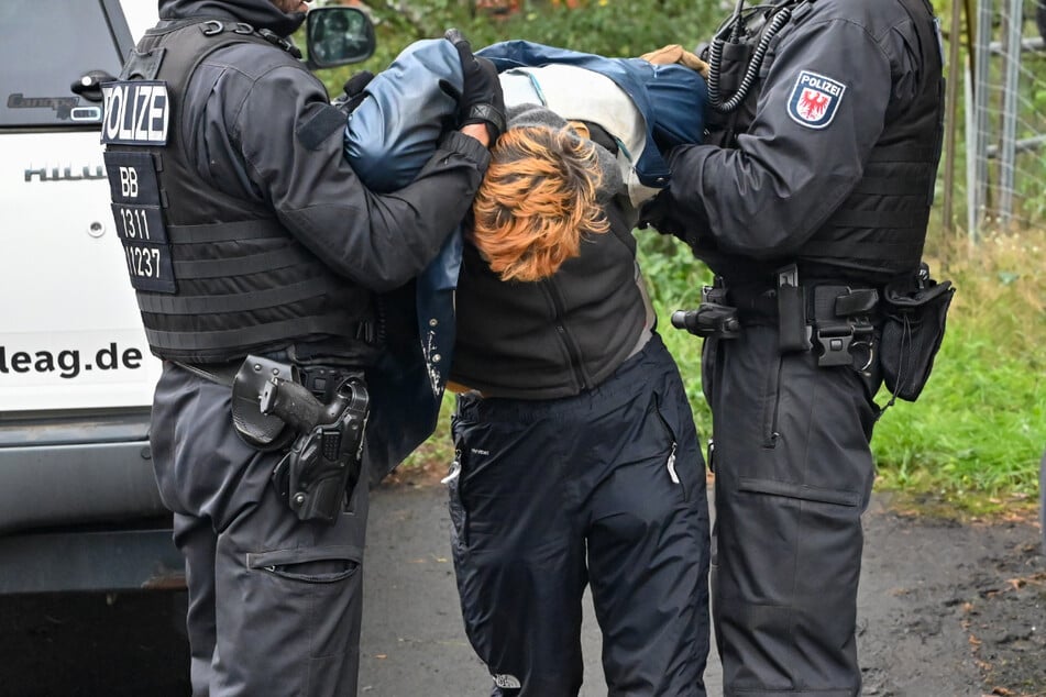 Polizisten bringen einen der Klimaaktivisten weg. Die Demonstranten hatten im September Gleise auf dem Gelände des Kraftwerks Jänschwalde blockiert.